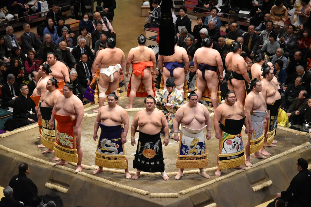 Sumo wrestlers gather in a circle around the gyōji (referee) in the dohyō-iri (ring-entering ceremony).