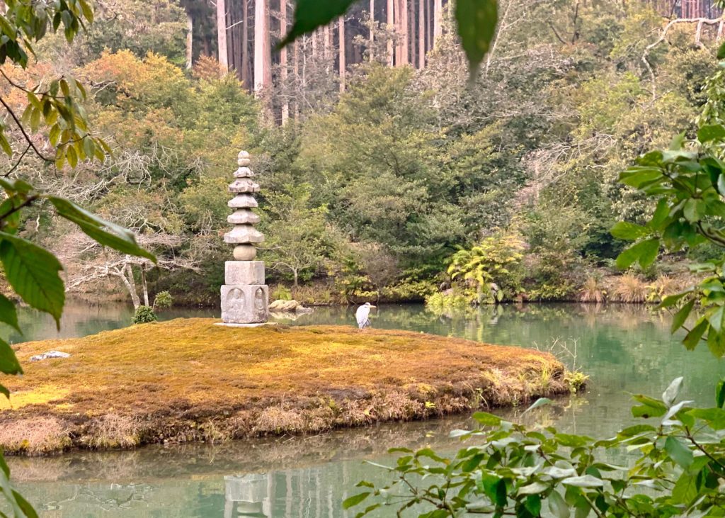 Hakuja-zuka and a resting grey heron in one of two ponds in Kinkaku-ji.